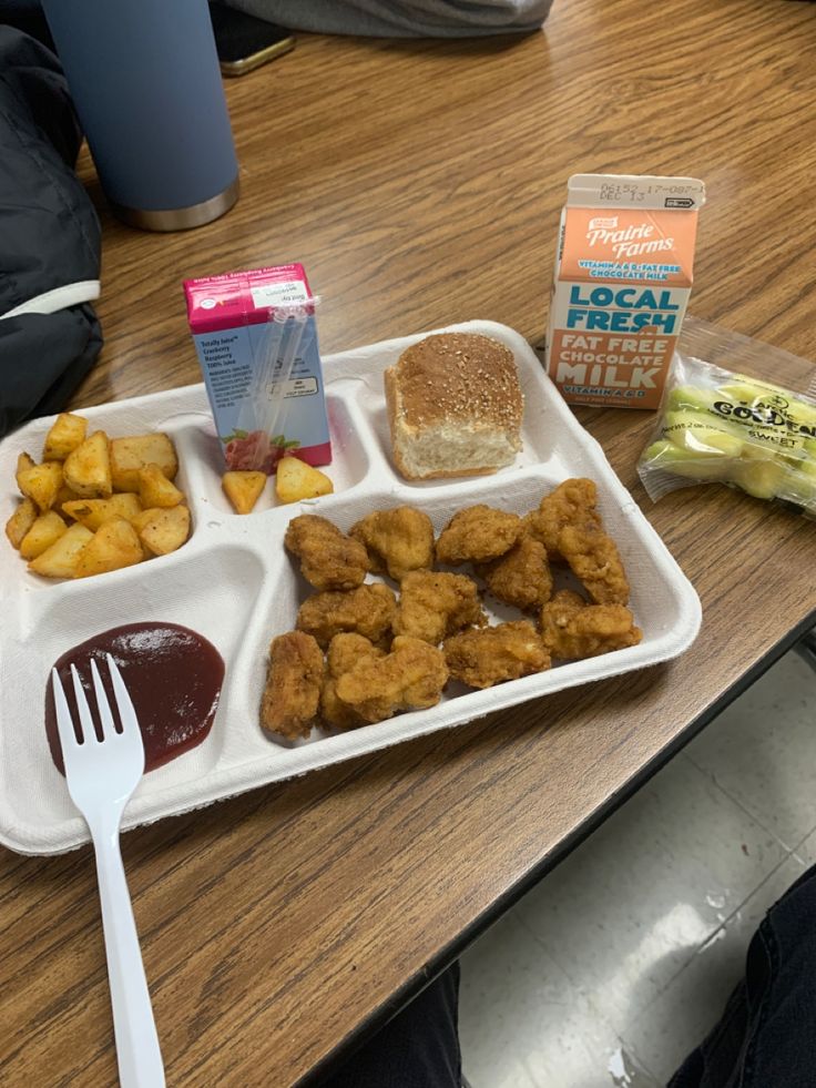 a lunch tray with tater tots, french fries and ketchup on it