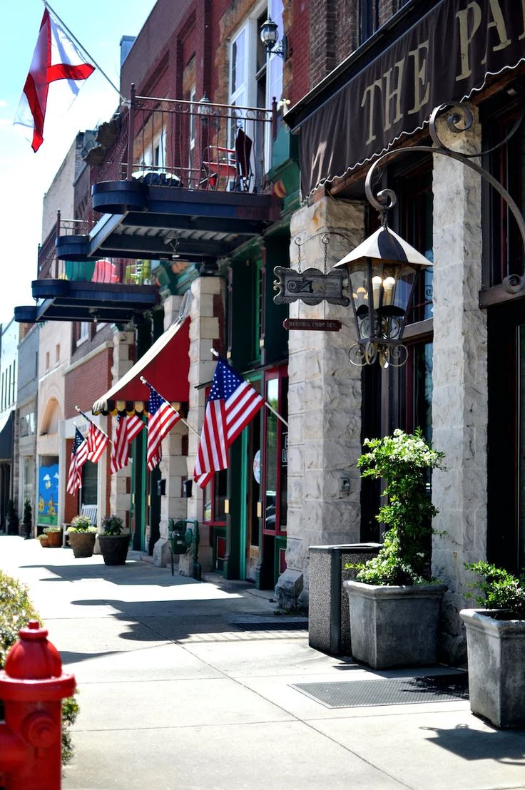 an american flag is hanging on the side of a building in front of a red fire hydrant