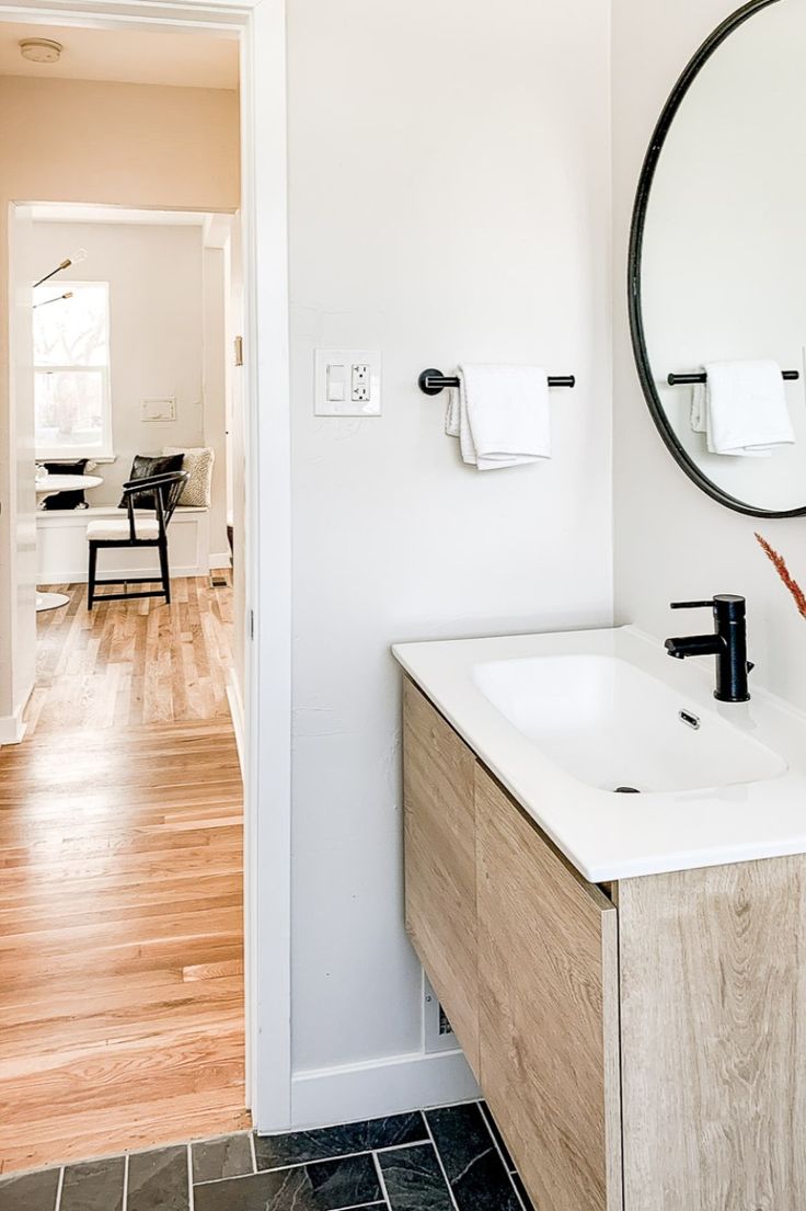 a bathroom with a sink, mirror and wood flooring in front of the door