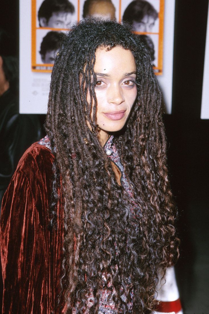 a woman with long curly hair standing in front of a poster