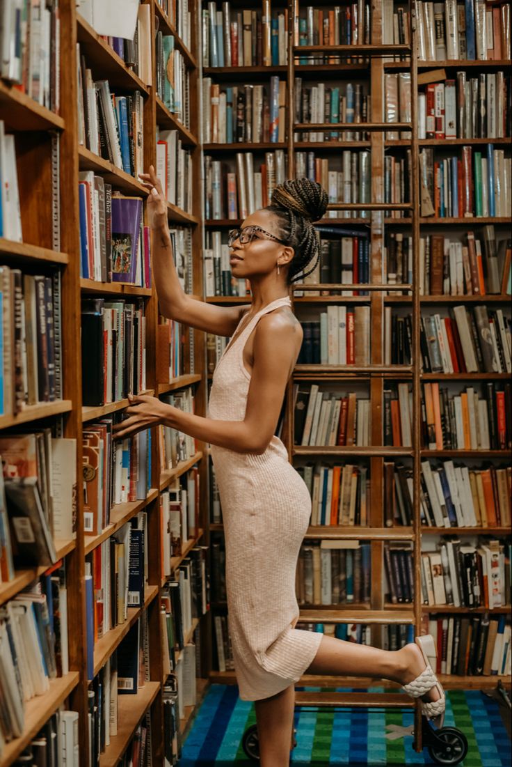 a woman leaning against a bookshelf in a library