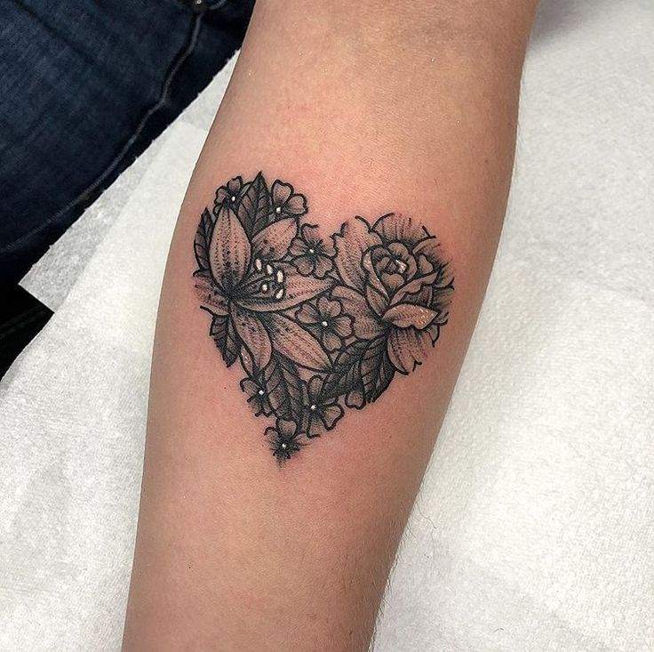 a black and white photo of a heart shaped tattoo with flowers on the left arm