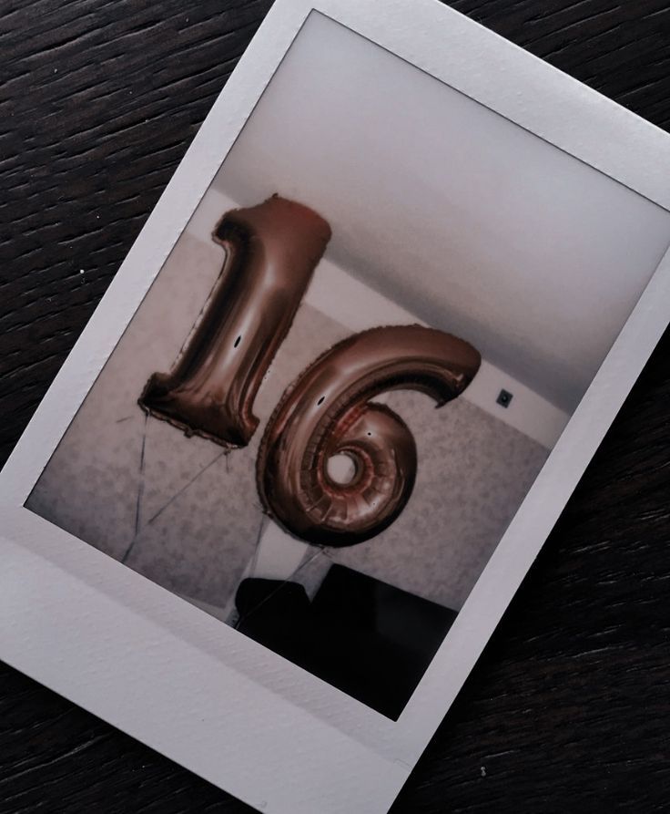 the number six balloon is in the shape of a large brown ballon, on top of a wooden table