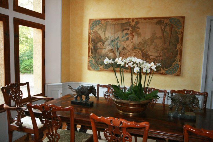 a dining room table with chairs and a vase filled with flowers on top of it