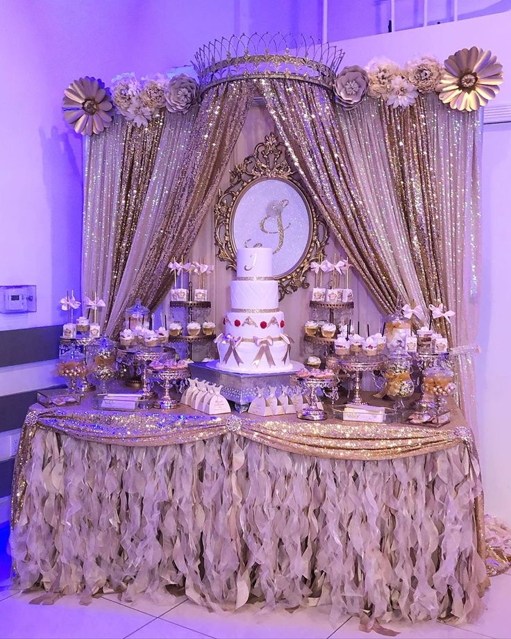 a table topped with a white cake covered in frosting and lots of gold decorations