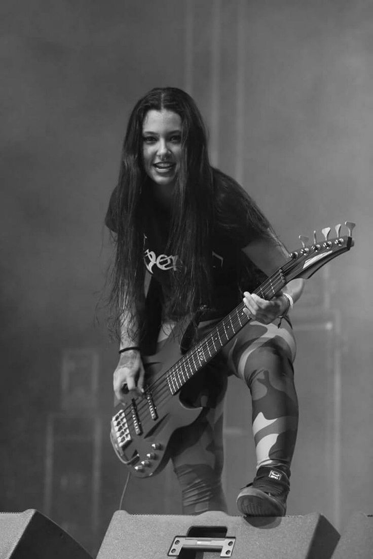 a man with long hair holding a guitar on top of a metal box at a concert