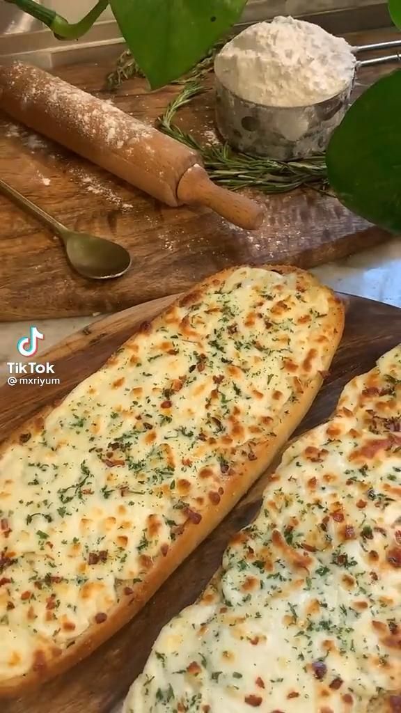 two slices of pizza sitting on top of a wooden cutting board next to some utensils