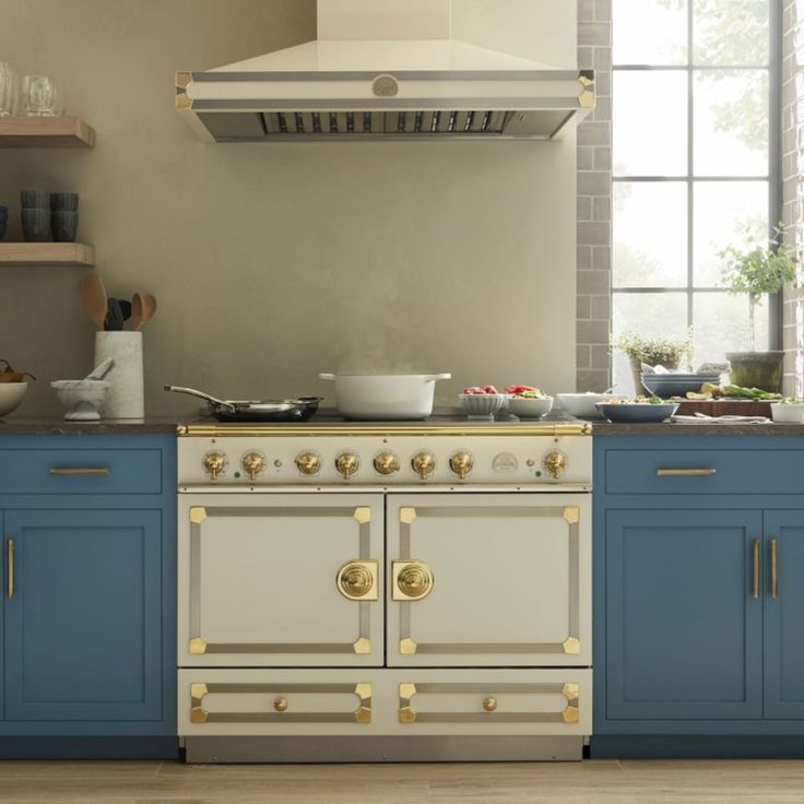 a stove top oven sitting inside of a kitchen next to blue cabinets and counter tops