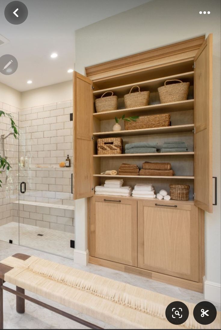 a bathroom with wooden cabinets and white tiled walls, along with a walk in shower