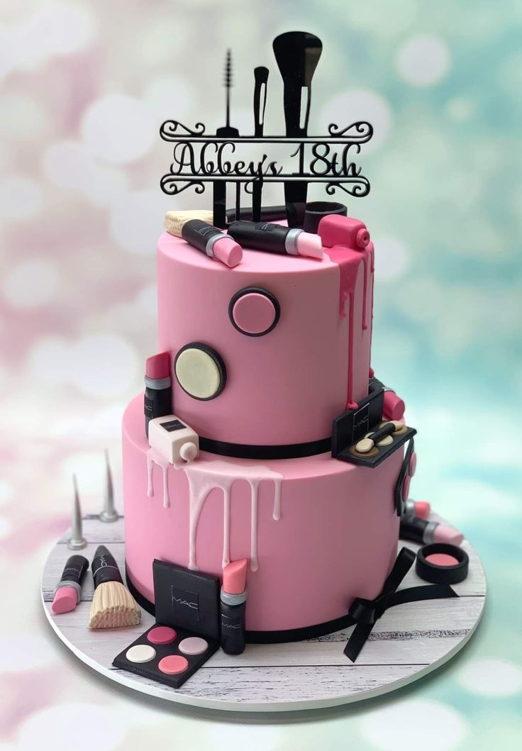 a three tiered cake with makeup and cosmetics on it's side, decorated in pink icing