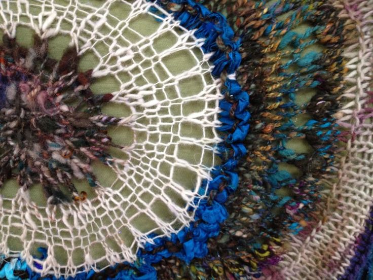 a close up view of a crocheted doily with blue and purple yarn