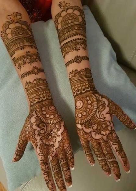 two hands with henna tattoos on them, one is showing off the intricate design