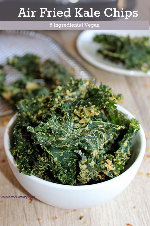 kale chips in a white bowl on top of a wooden table with text overlay that says air fried kale chips