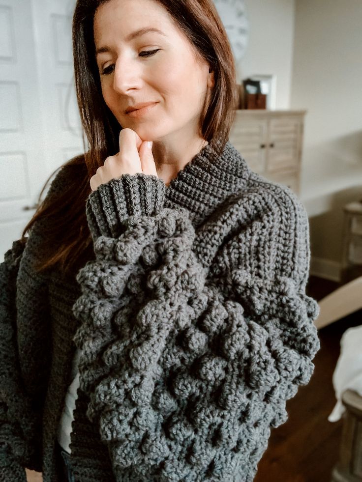 a woman is wearing a gray sweater and posing for the camera