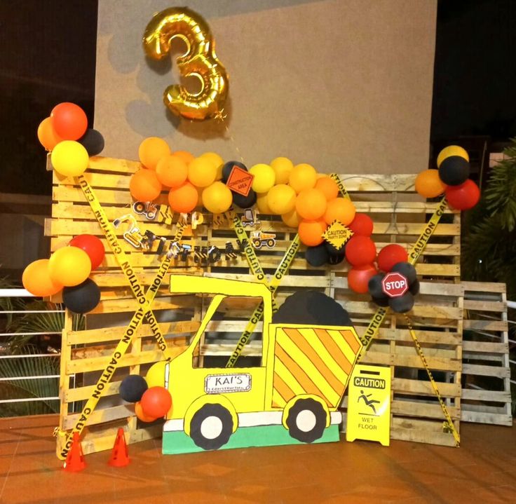 a construction truck themed birthday party with balloons and streamers on the back wall,