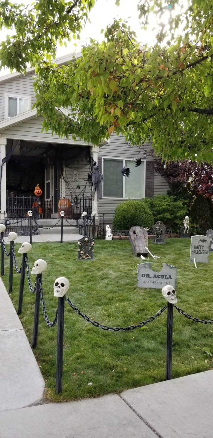 halloween decorations on the lawn in front of a house with ghost heads and tombstones