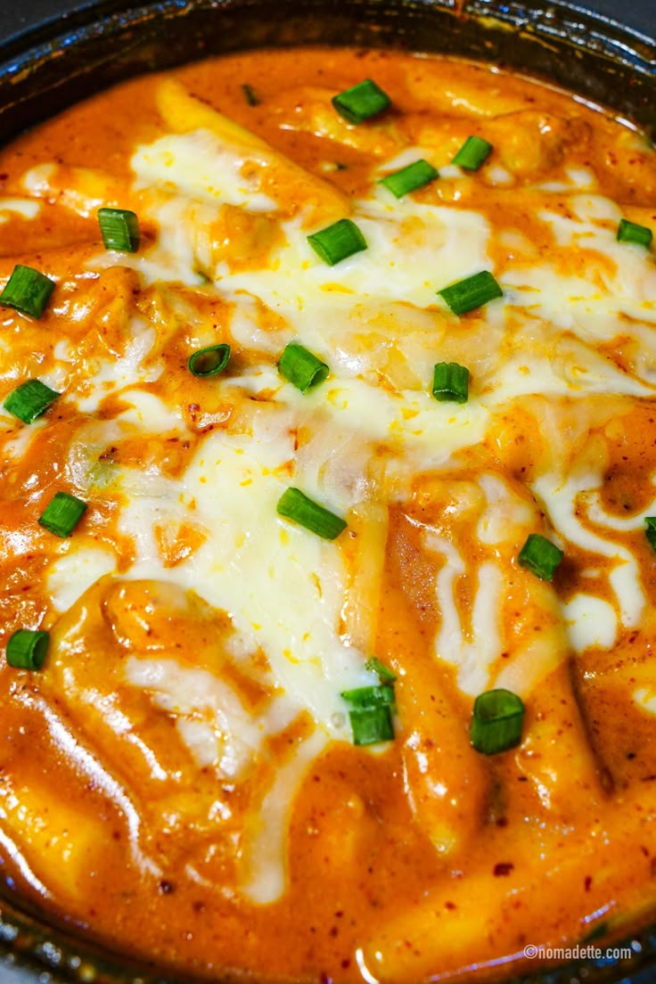 a close up of a casserole dish with cheese and green onions on top