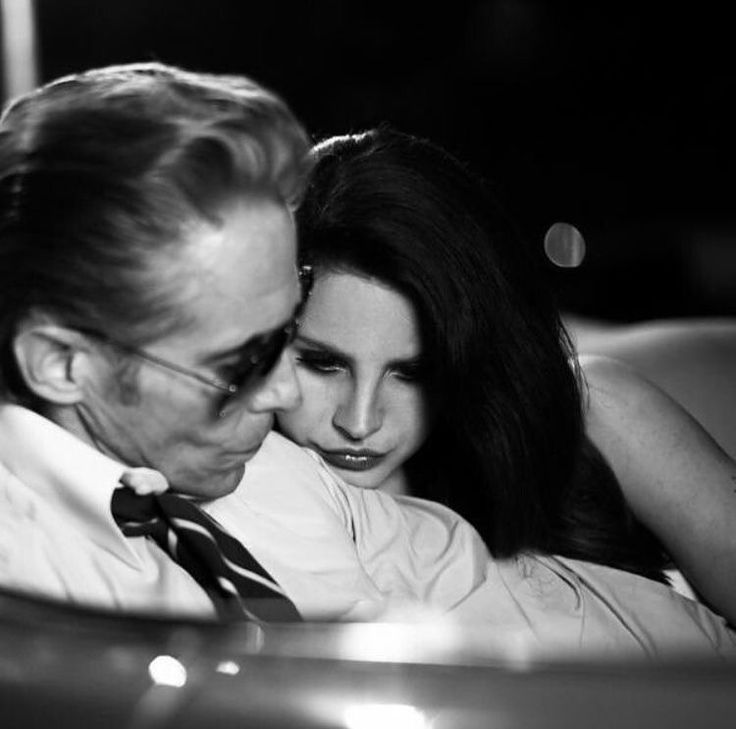 a man and woman sitting in a car looking into each other's eyes while they are cuddling