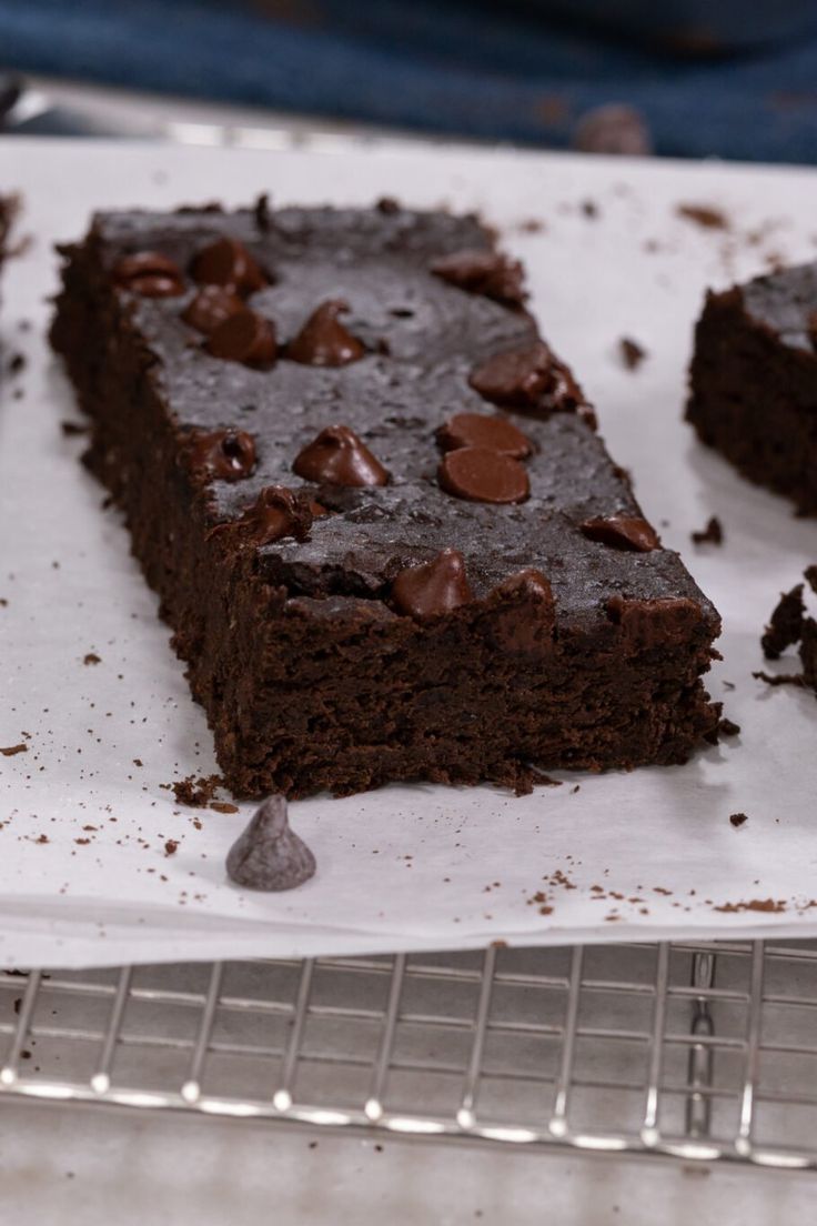 two pieces of chocolate cake sitting on top of a cooling rack