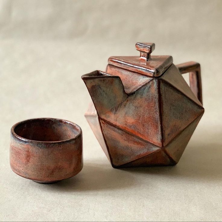 a teapot and cup sitting on top of a table next to an empty bowl