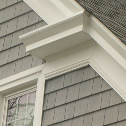 the corner of a house with a bird perched on it's window sill