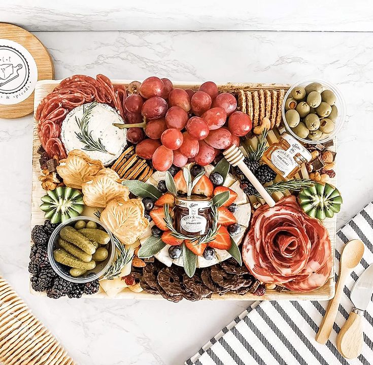 a platter filled with meats, cheeses and olives on a table