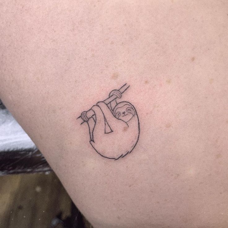 a small slotty tattoo on the back of a woman's left arm and shoulder