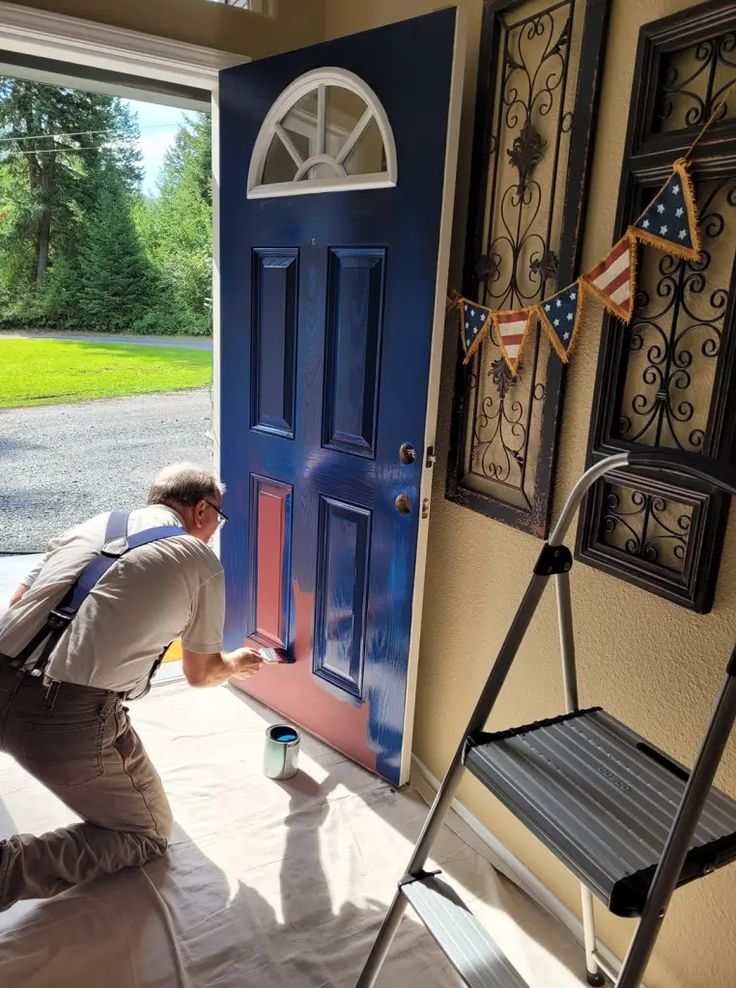 a man painting the front door of a house