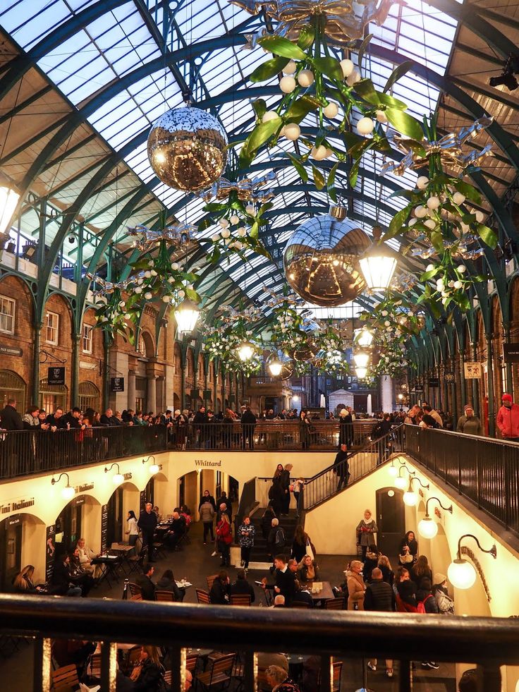 the inside of a building with people sitting at tables and hanging lights in it's ceiling