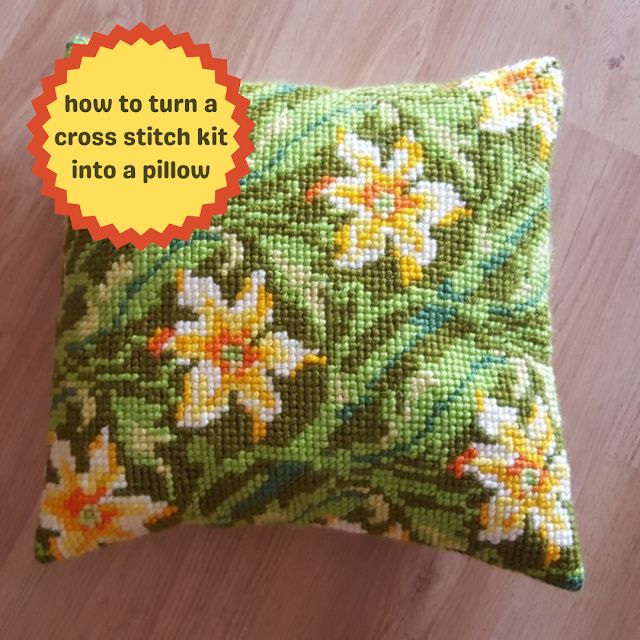 a cross stitch pillow on a wooden floor with the words how to turn a cross stitch kit into a pillow