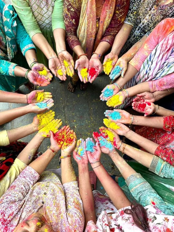 many people are holding their hands together in the middle of a circle with colored powder all over them