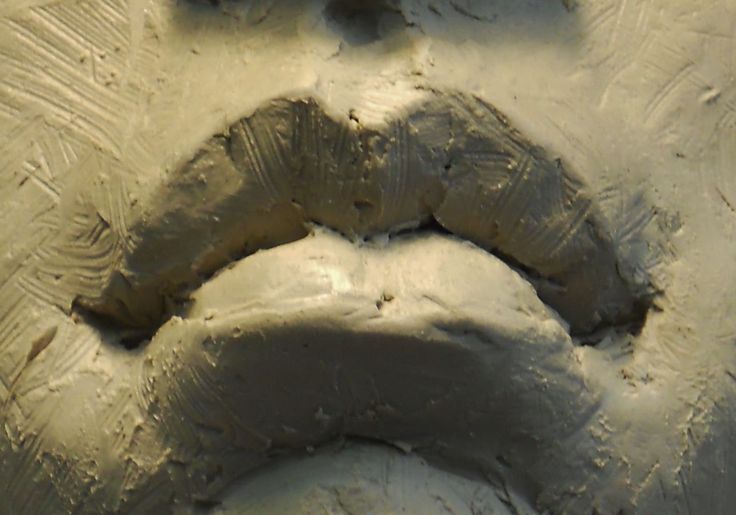 a face made out of clay on a white surface with the shape of a woman's mouth