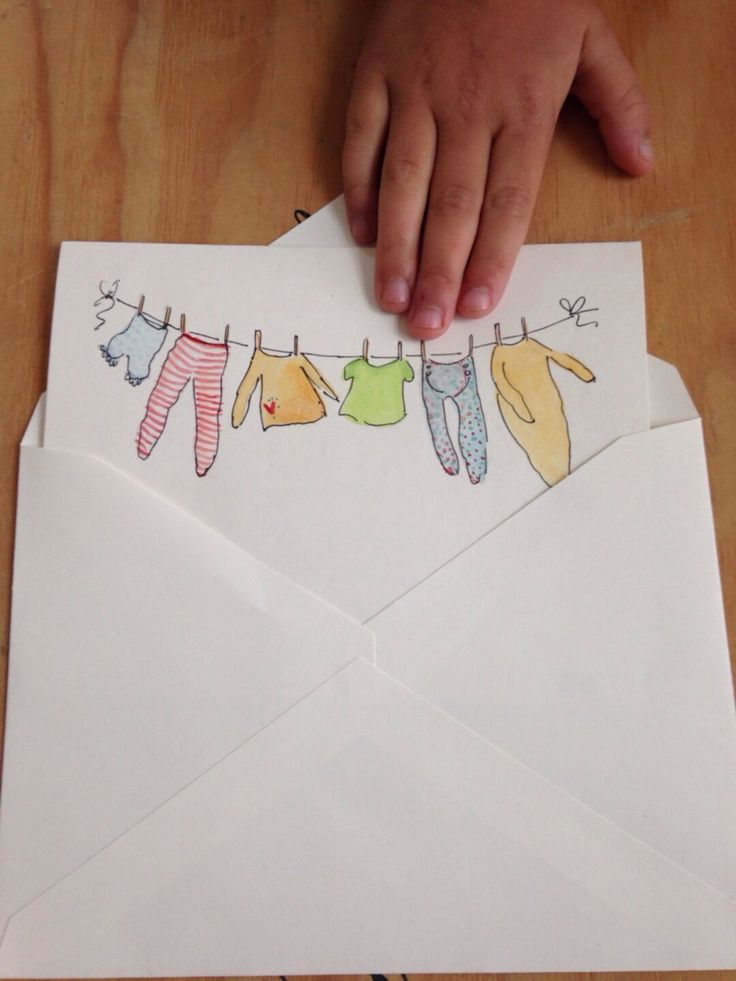 a child's hand on top of an envelope with clothes hanging from it