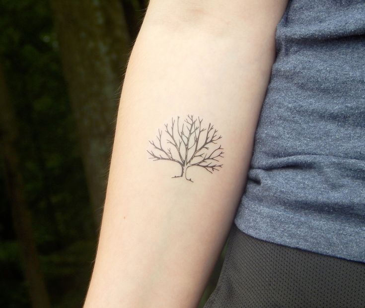 a woman's arm with a small tree tattoo on the left side of her arm