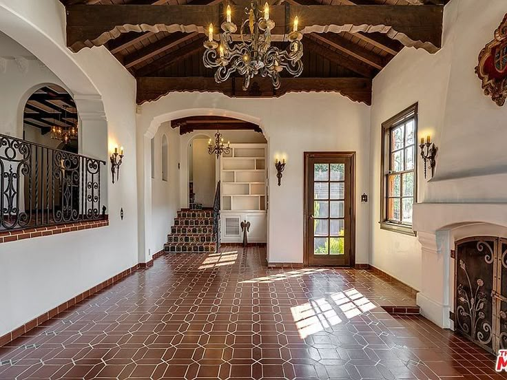 an empty room with red tile flooring and chandelier