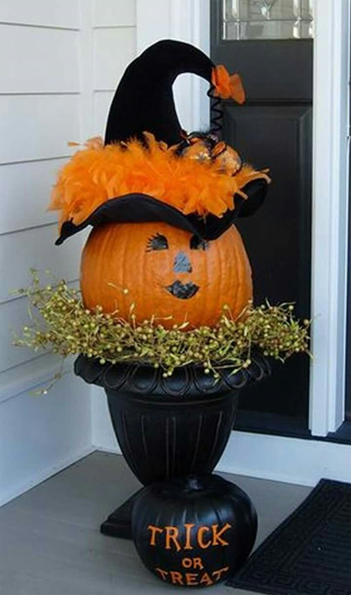 a decorated pumpkin sitting on top of a black vase in front of a door with the words trick or treat written on it