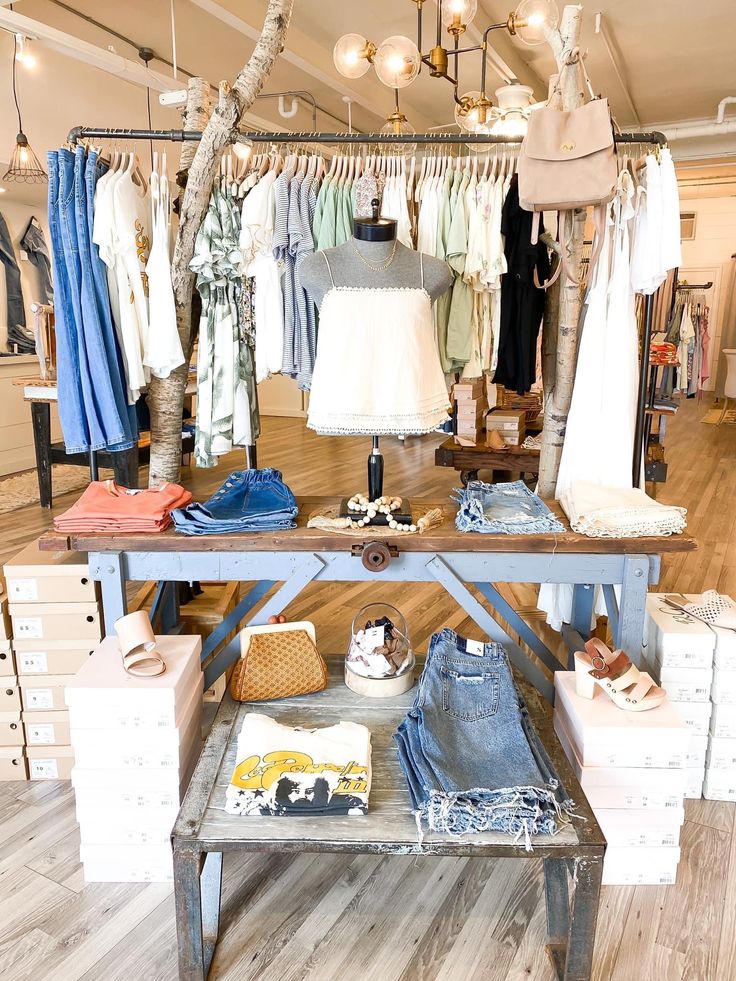 a clothing store display with clothes and shoes on the table in front of it,