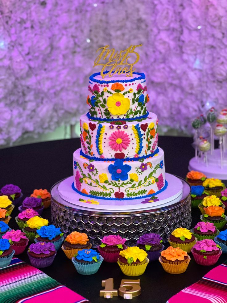 a multi - tiered cake and cupcakes on a table