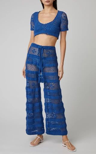 a woman wearing blue crochet pants and crop top