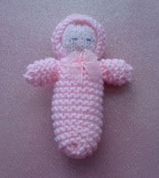 a pink crocheted baby doll laying on the ground with its arms and legs wrapped around it