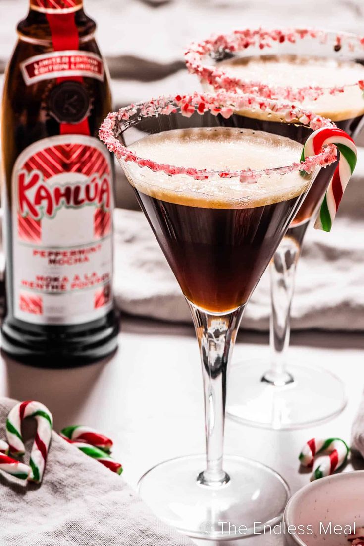 two martini glasses with candy canes and peppermint garnish on the rim