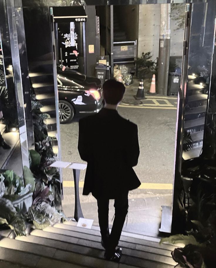 a man in a suit is walking up the stairs to an entrance at night time