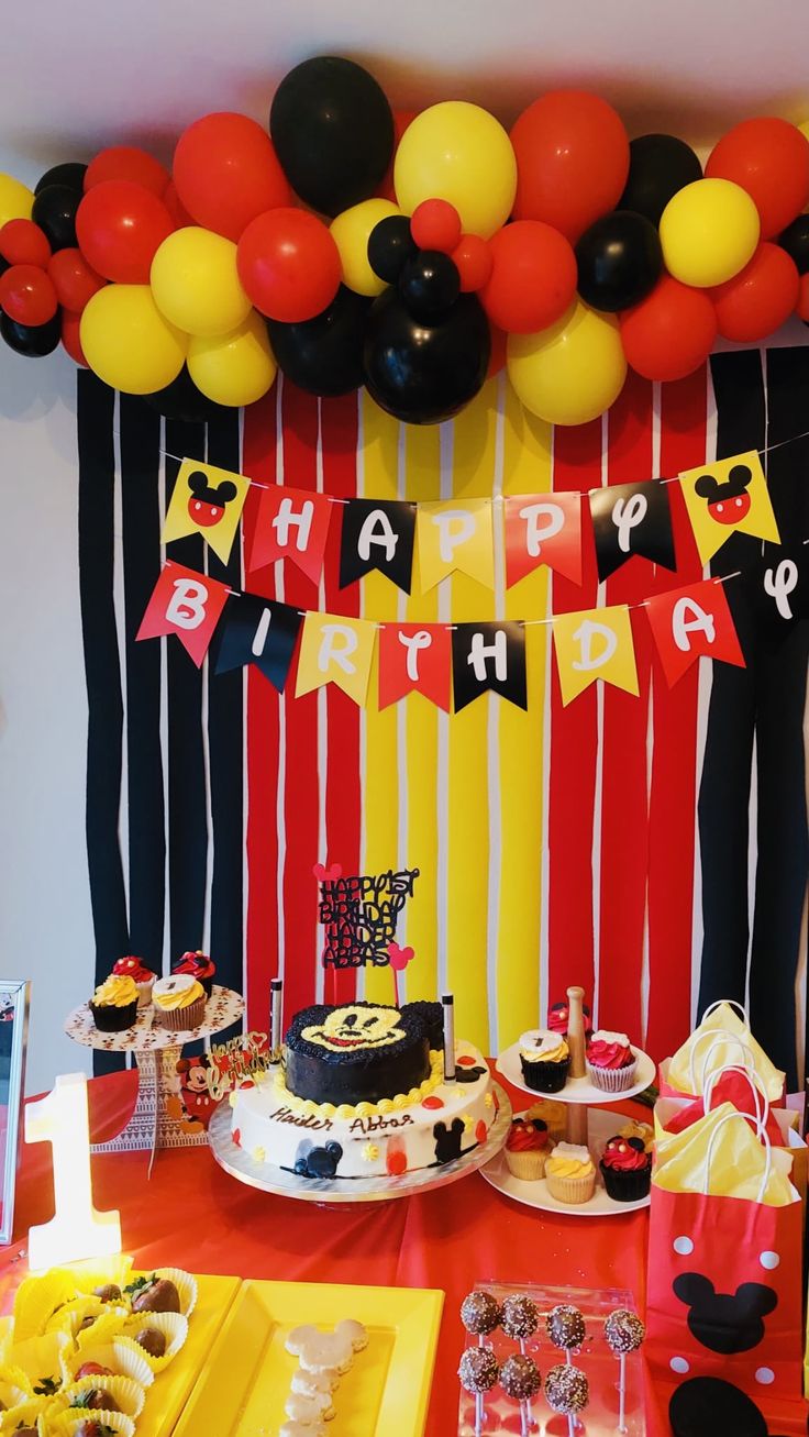 a mickey mouse themed birthday party with balloons and desserts on the table, along with decorations