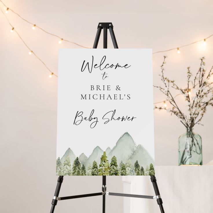 an easel with a welcome sign on it next to a vase and string lights