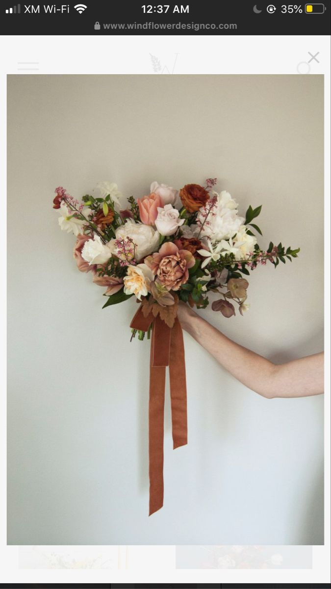 a bouquet of flowers is being held up by someone's hand on the wall