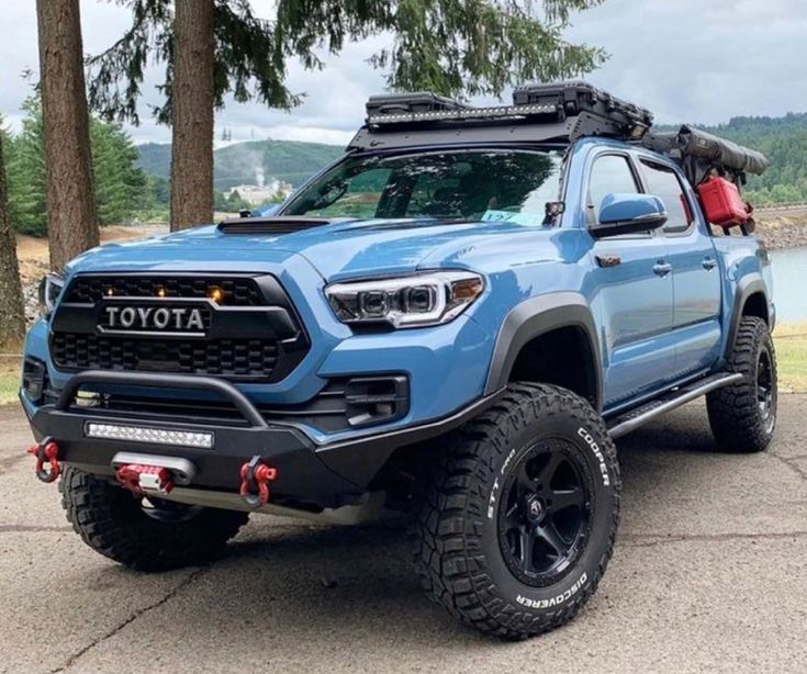 a blue toyota pickup truck parked in front of some trees