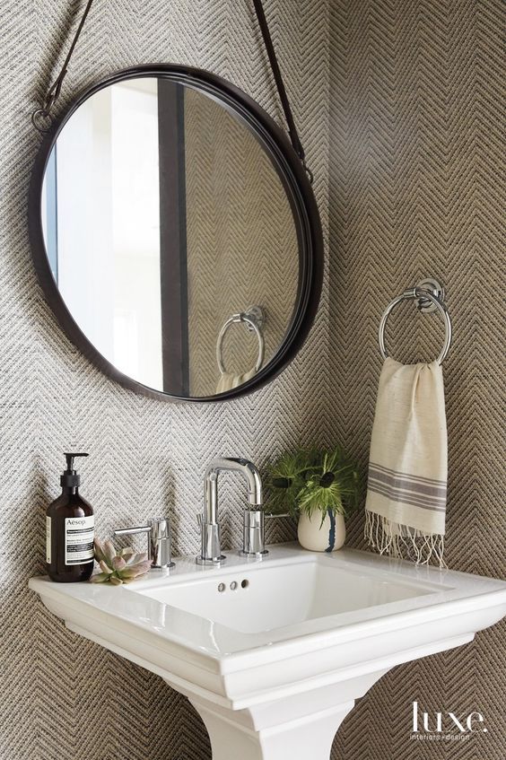 a white sink sitting under a round mirror