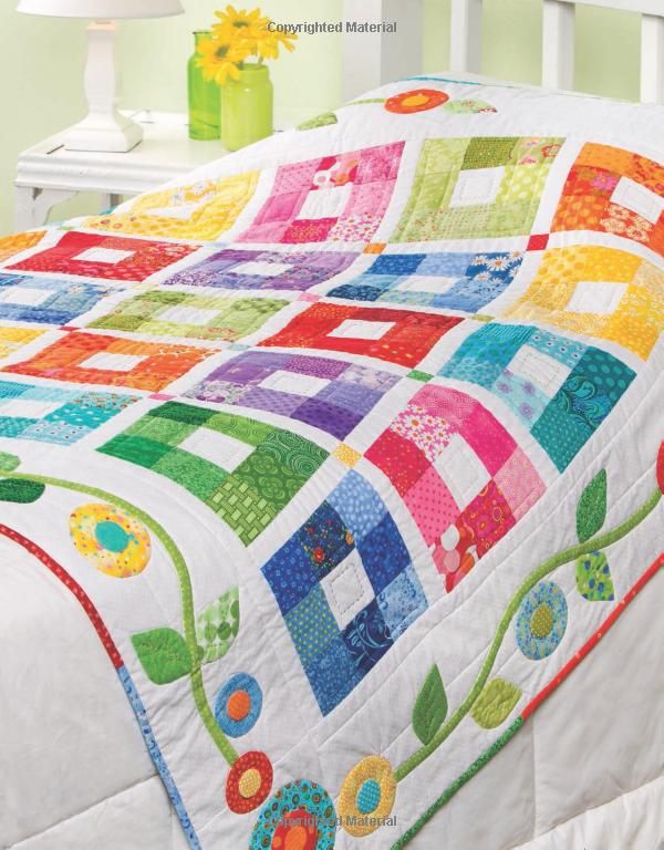 a white bed topped with a colorful quilt