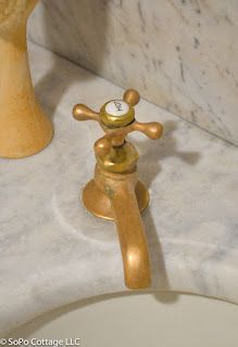 a gold faucet sitting on top of a white sink next to a yellow vase