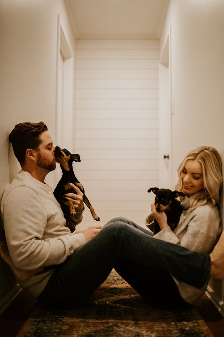 a man and woman are sitting on the floor with their small dogs in their lap